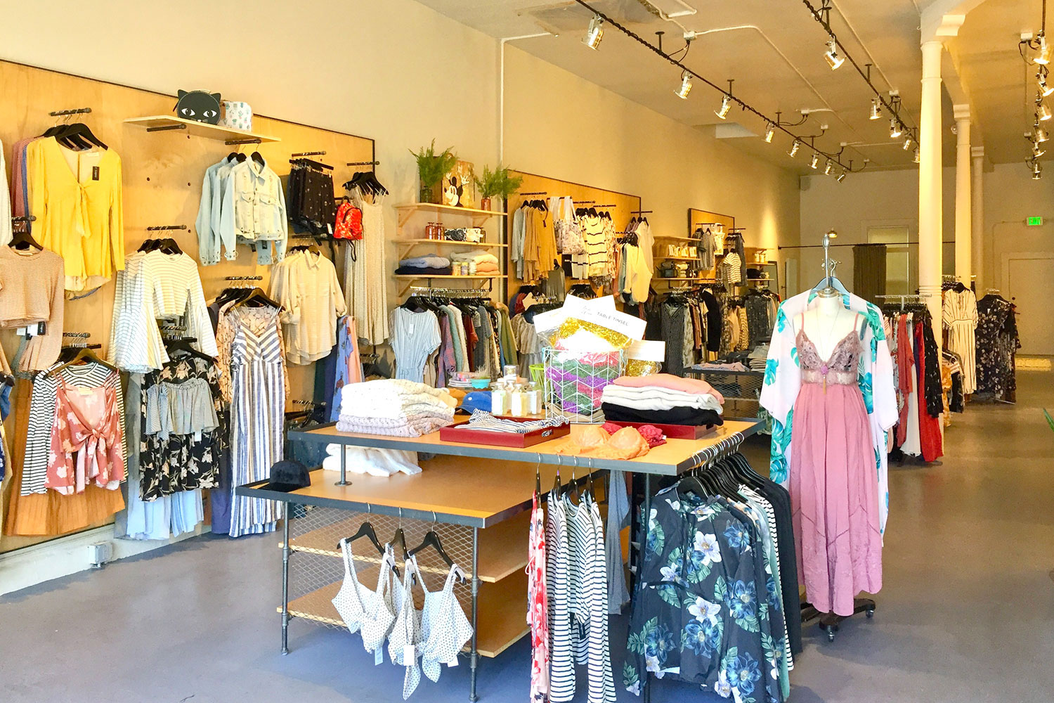 Retail store interior. High ceilings, unique clothing display racks. canister-style light fixtures. White walls with polished concrete floor.