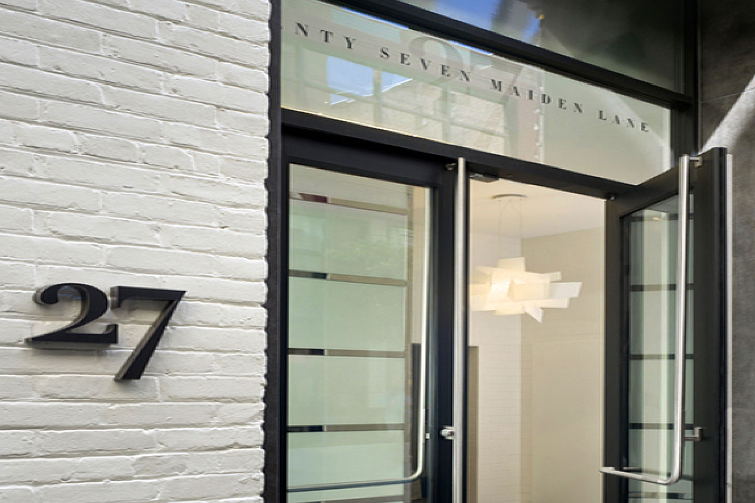 Exterior office building. Painted white with black trim. Oversized glass entry doors, designer lightning, and custom signage.