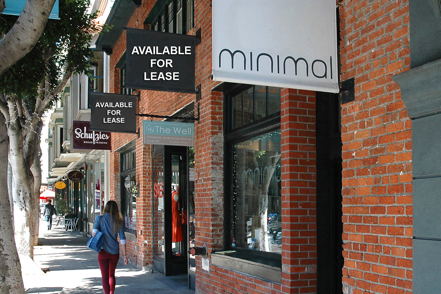 Ground floor retail store. Two-story brick building with large display windows and custom signs. Sidewalk entry, high foot traffic location.