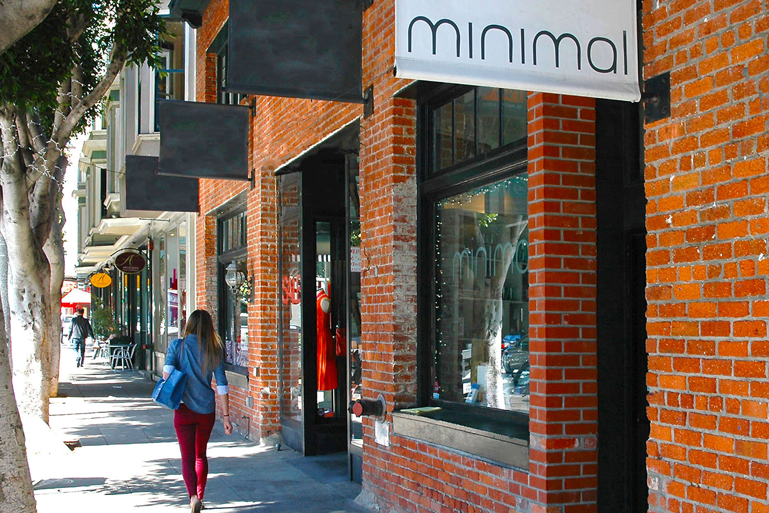 Ground floor retail store. Two-story brick building with large display windows and custom signs. Sidewalk entry, high foot traffic location.